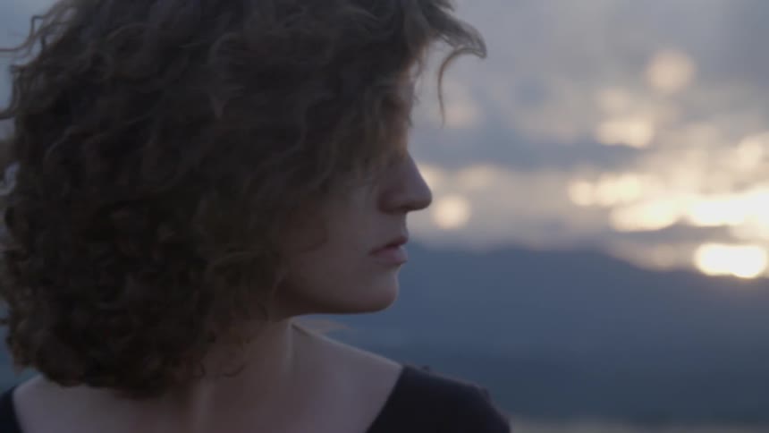 A woman slowly turns her head to look over her shoulder late in the afternoon on a cloudy day