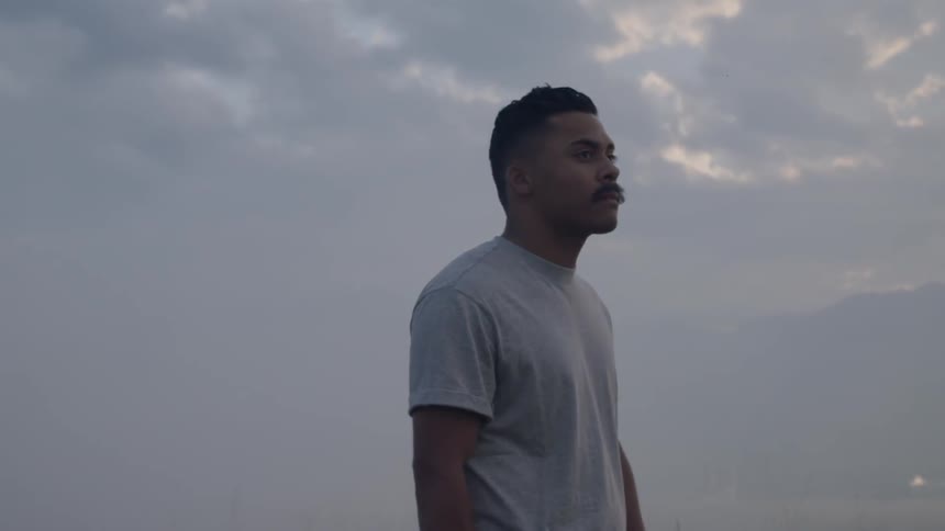 A man looking around at his surroundings near the mountains on a cloudy day