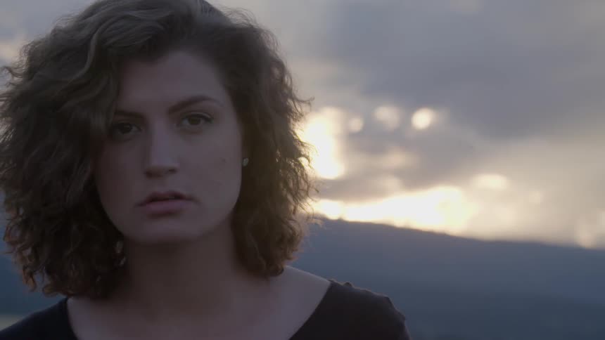 A woman with clouds in the background at sunset