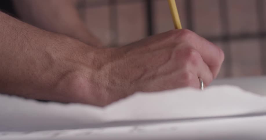 Man uses a pencil to draw on a piece of paper