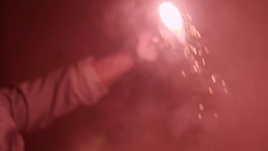 A crouching man holds a flare gun and slowly lifts it