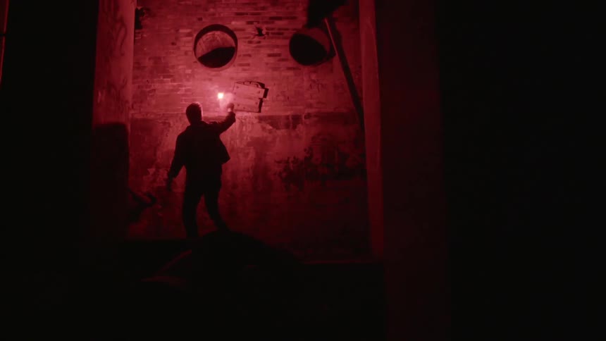 A man holding a flare up to a brick wall