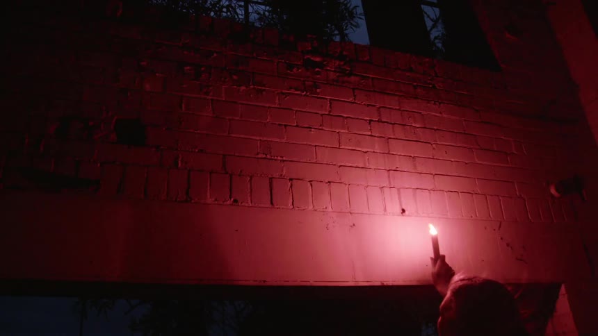 A woman holding a candle up to a brick wall