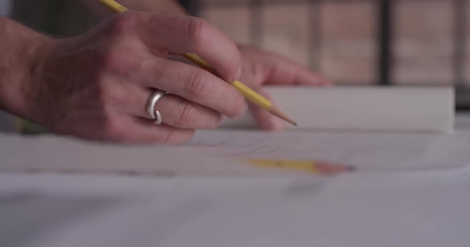 A person unfurling some paper and setting pencils on it