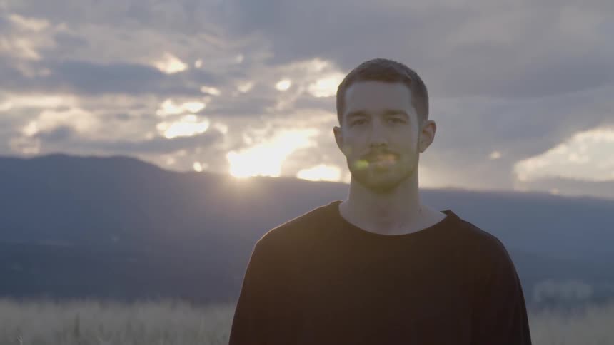 A man is standing outdoors while the sun is setting