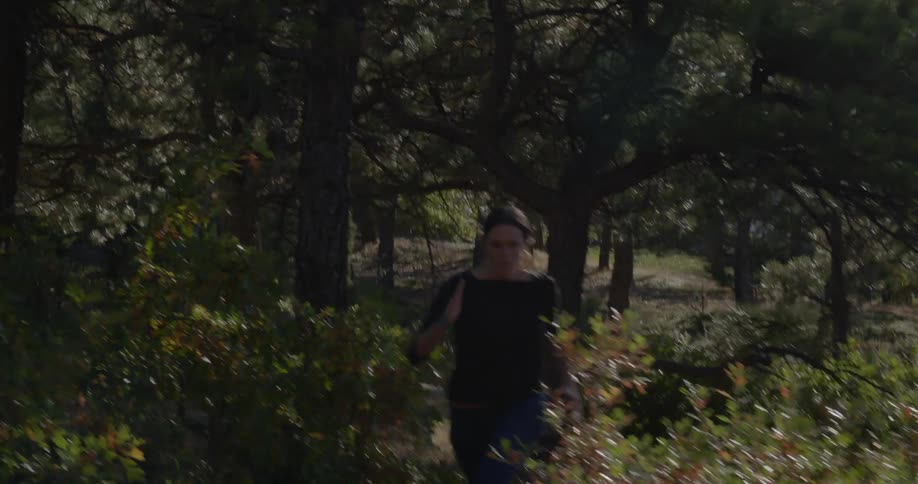 A woman runs along a path through trees and bushes
