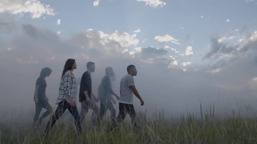 A group of young people walk through a foggy field
