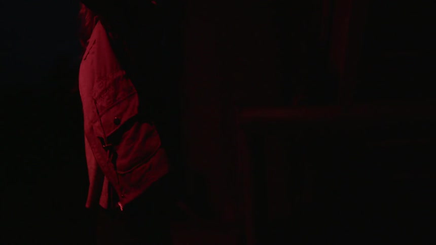 A woman raises a torch up to look at something in a dark room