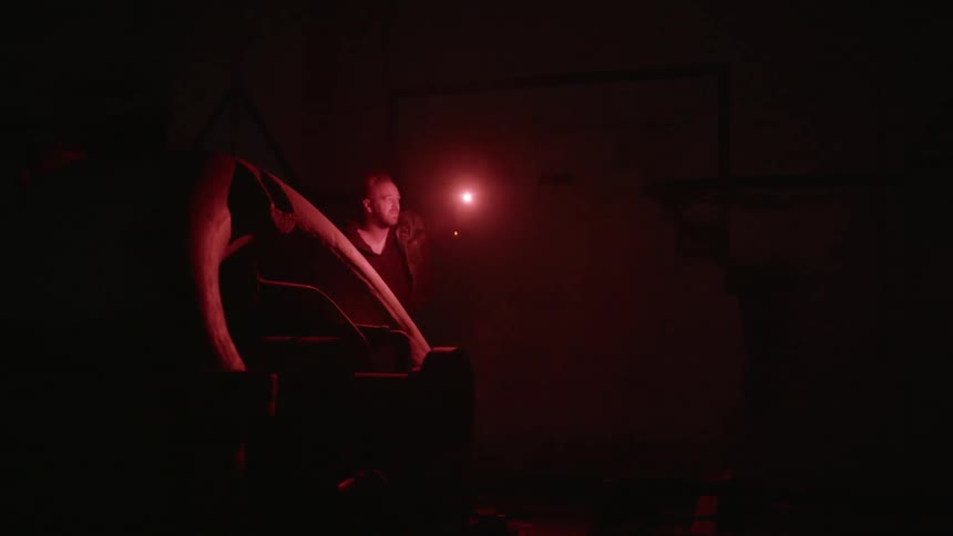 Man uses a red emergency flare while walking inside a dark basement