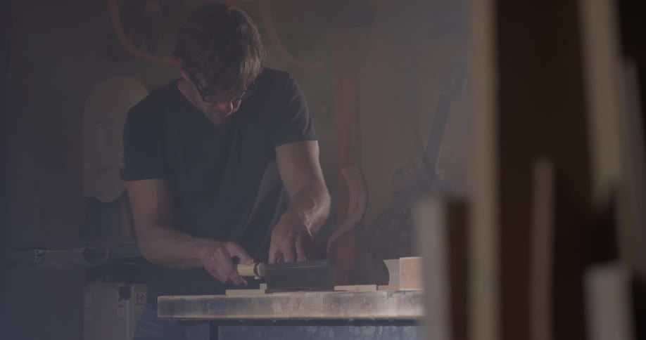 A man working on a piece of wood with a saw