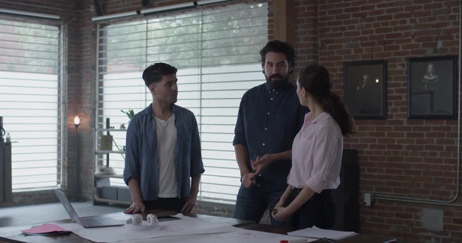 A group of three people talking about plans on a piece of paper