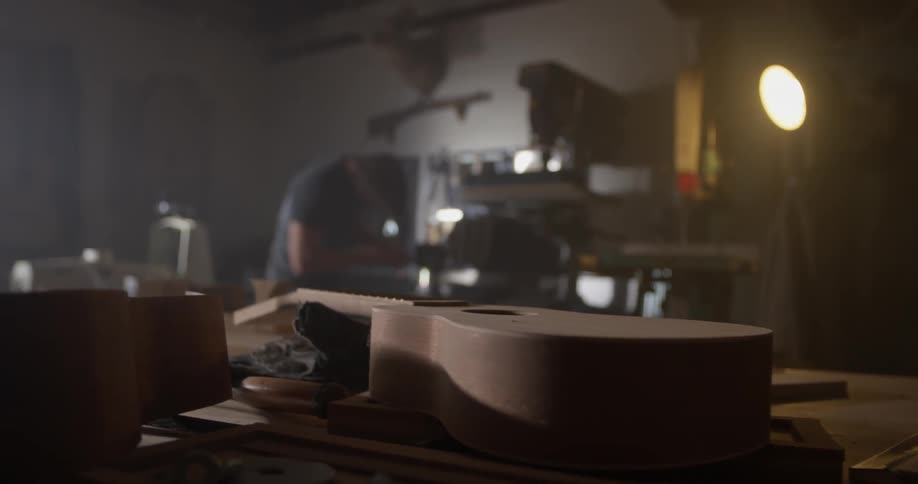 A man uses tools to make something in a dark workroom