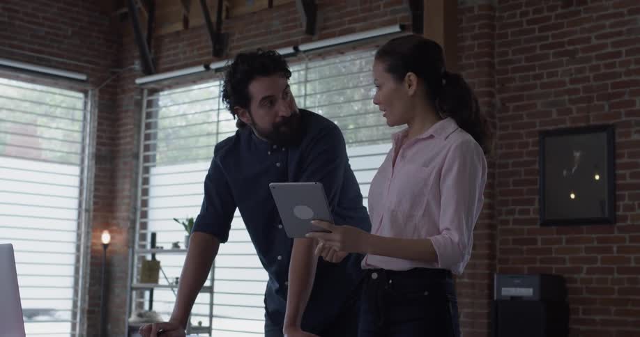 A man sketching on a piece of paper while a woman shows him something