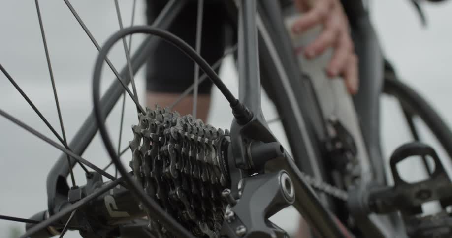 A person standing next to their bike and grabbing their water bottle