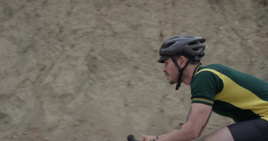A cyclist rides near a sandy hill