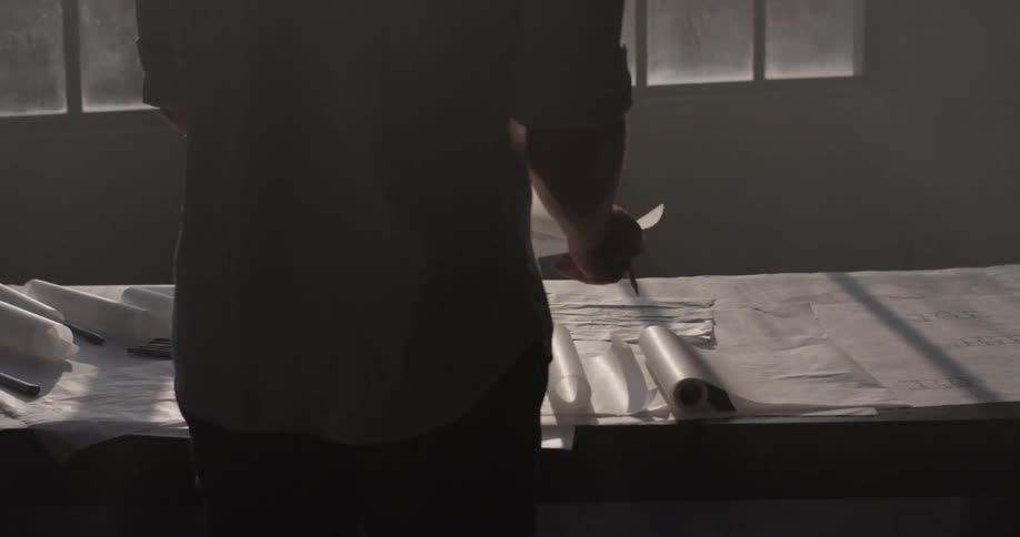 A man was rolling up a piece of paper on a table
