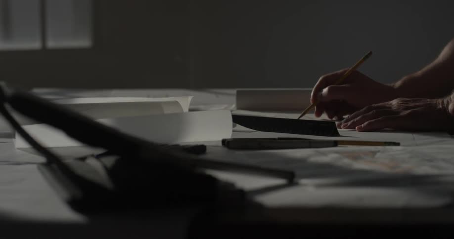 A person drawing on a blueprint on a desk