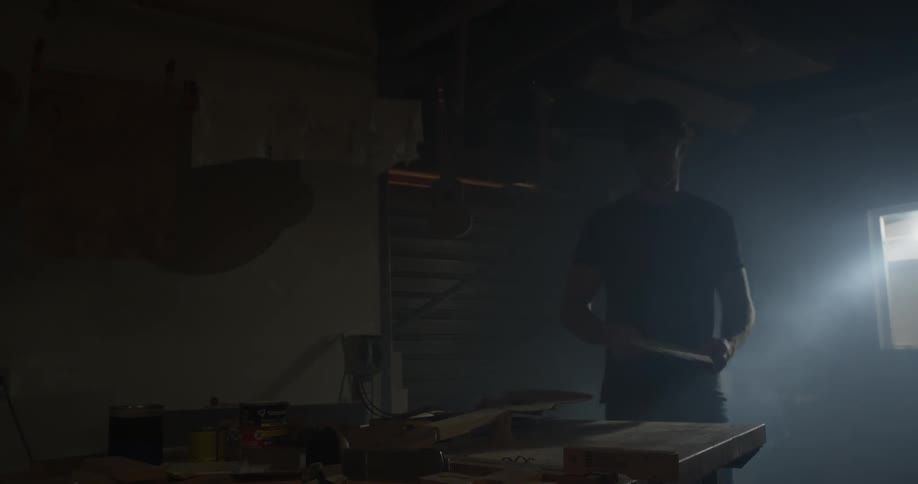 A man opens his garage and holds some tools