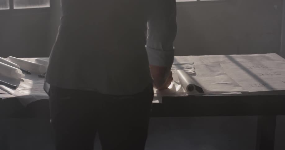 A person is standing at a table with rolls of paper
