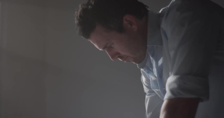 A mean in a blue dress shirt leans over