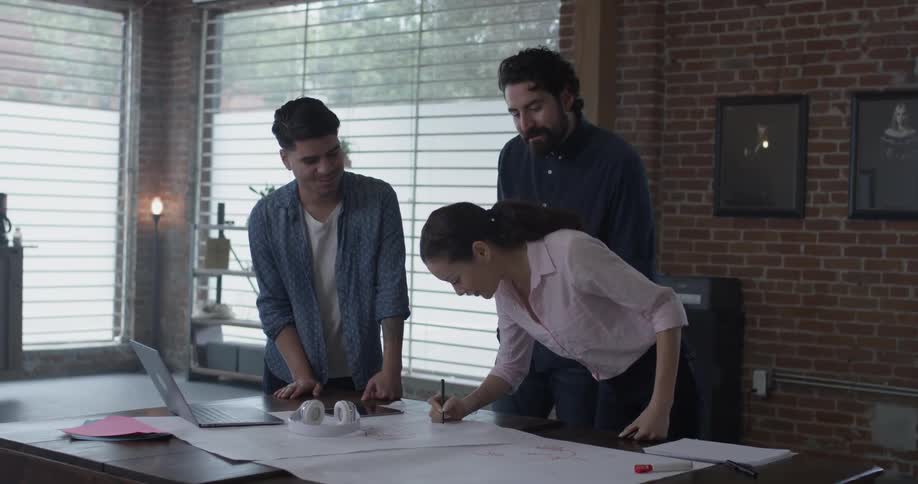 Three people making notes on a table lined with paper
