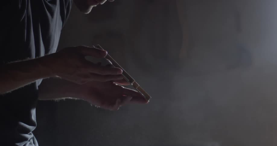 A man blowing some dust off a piece of wood