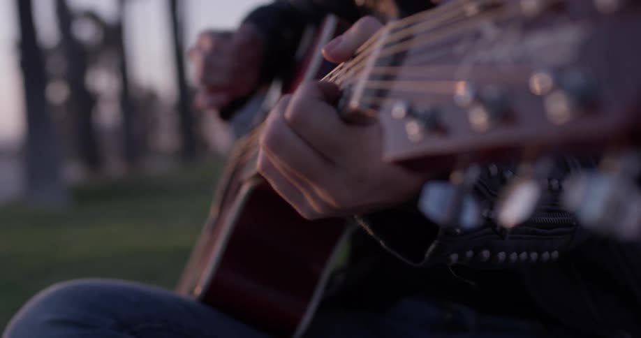 A woman is playing the guitar on the grass