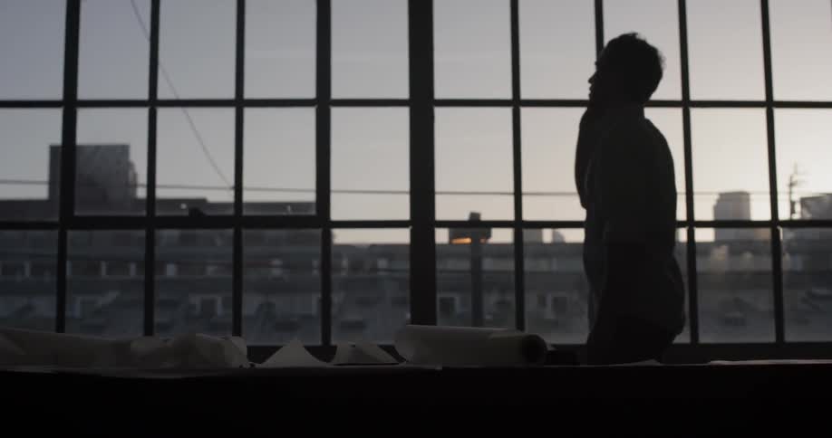 Man talking on the phone while standing in front of a large window