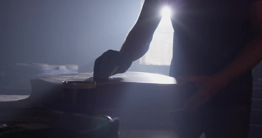 A person staining a piece of wood in a shop