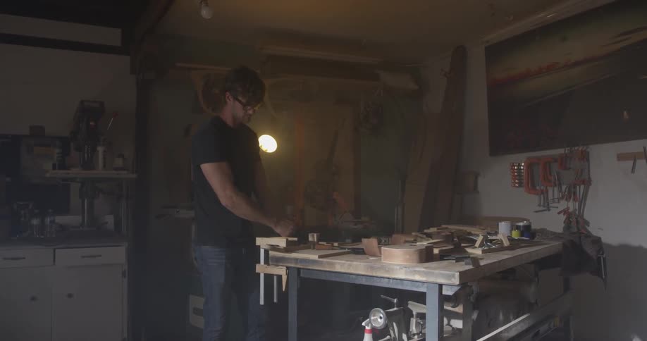 A brown haired man works diligently in his workshop late into the night