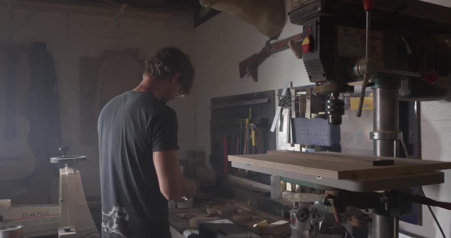 A man grabs a tool from the wall