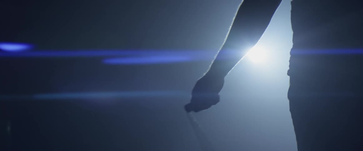 A person jumps rope in the dark with a light behind them