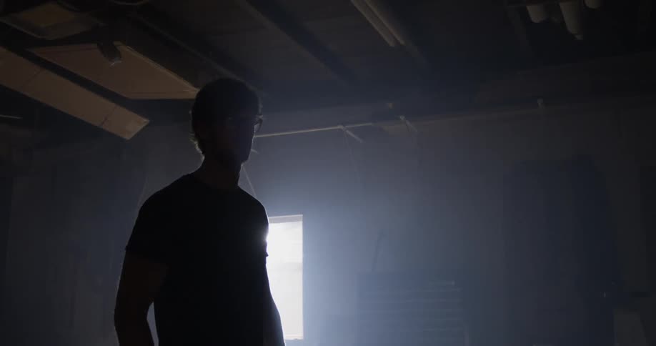 A young man walks through a dark garage