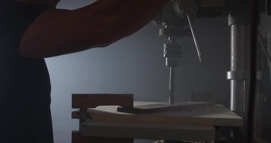 A man uses a drill press