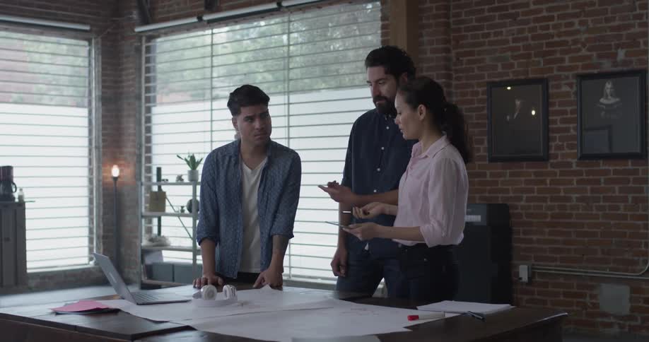Three people discussing paperwork on a table