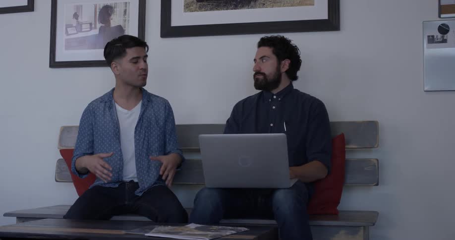Two men are sitting down and talking