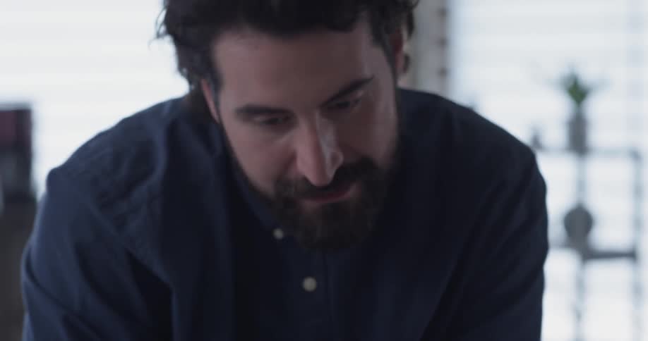 Man points to a laptop while talking to someone off screen
