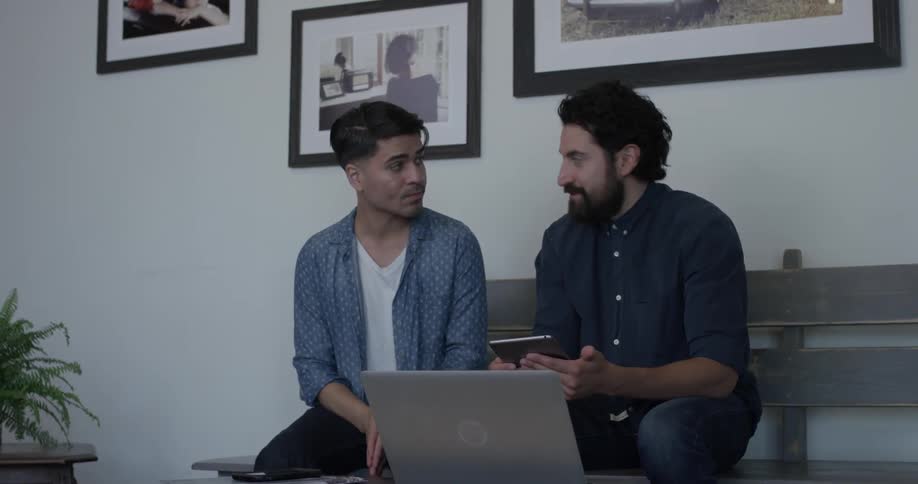 Two man sitting on a bench look at a tablet