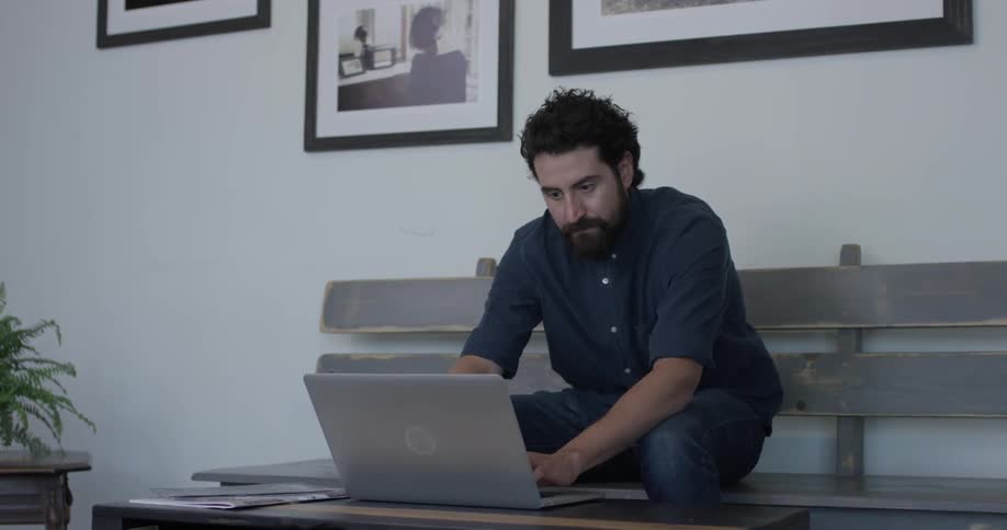A man is typing on a laptop indoors