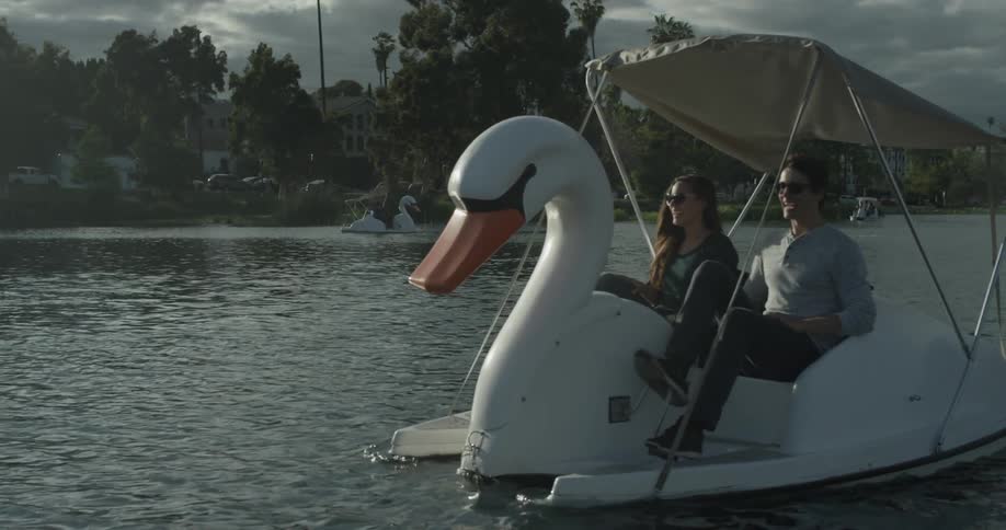 Two people pedaling a pedal swan boat on a lake