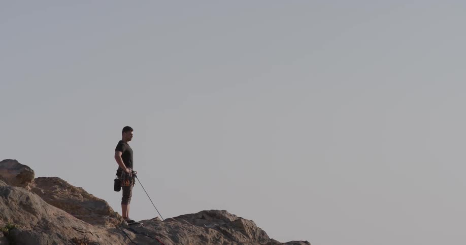 A man that has rope hanging off of a cliff