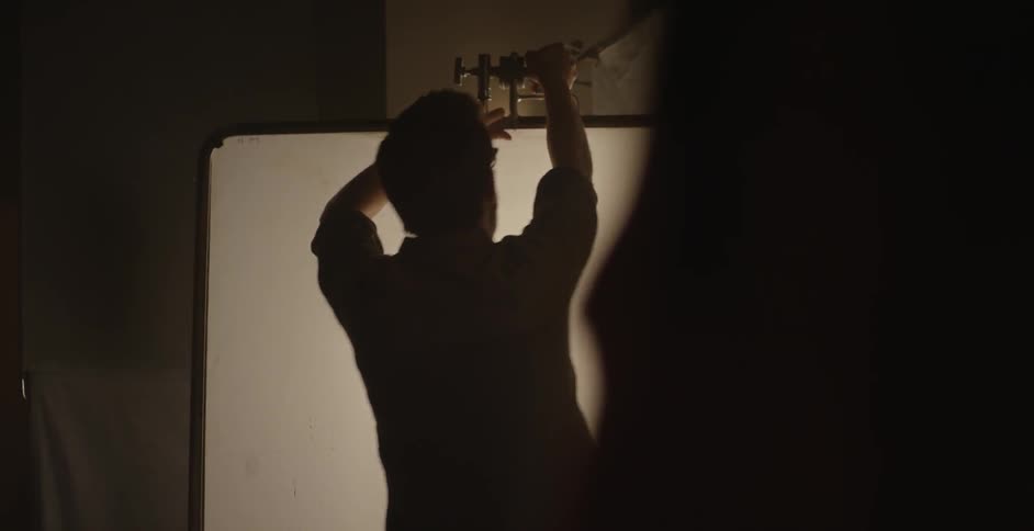 A man hanging a white screen indoors