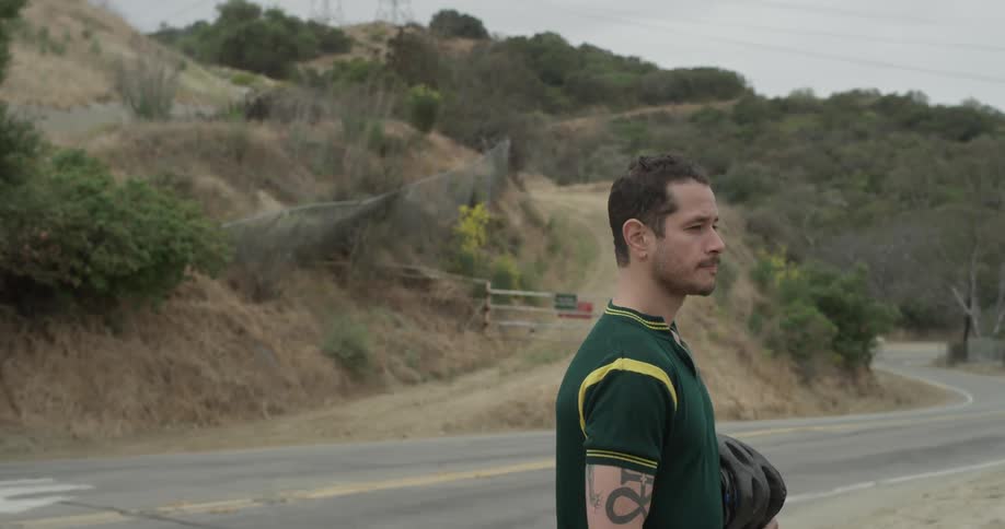 A man nodding his head standing next to a road
