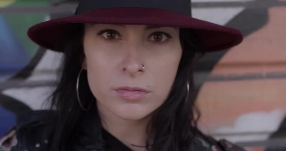 A woman wearing a hat looking into the distance and blinking