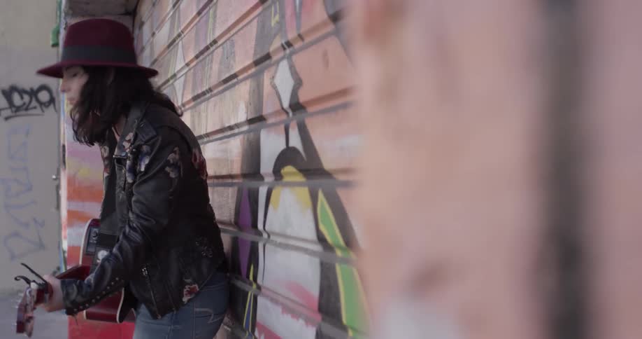 A woman standing on the street playing a guitar