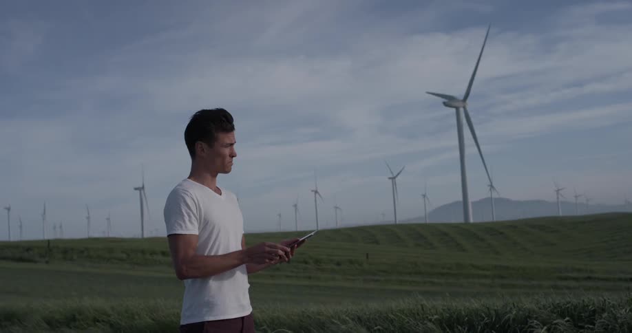 Man Driving Electric Car Through Wind Farm