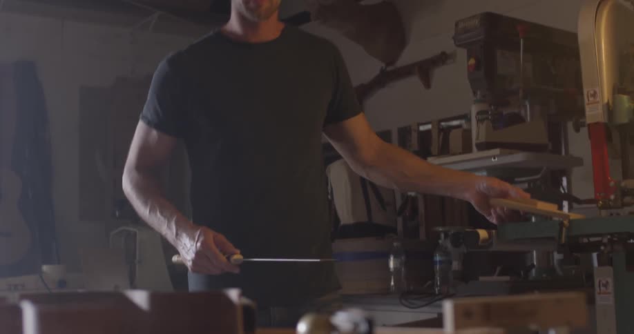 A woodworker measuring and working on a project in a studio