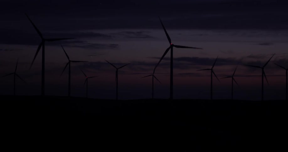 Windmills that are rotating on a grassy field