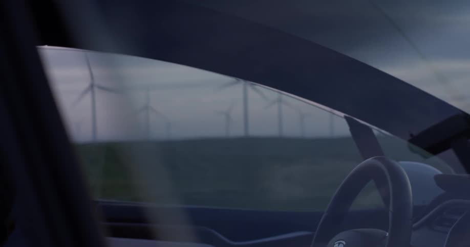 Man getting out of a car near a wind farm