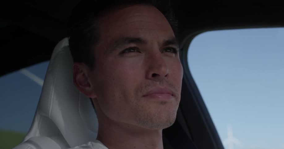 Man Driving Electric Car Through Wind Farm